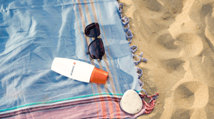 Sunglasses and sunscreen on a blanket at the beach